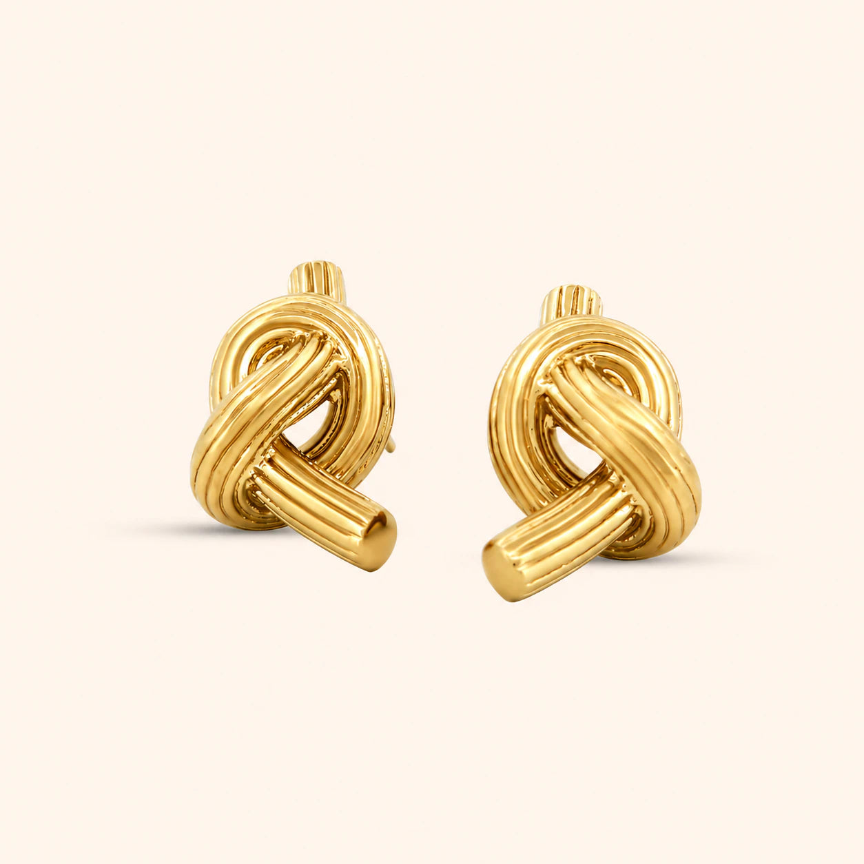 A pair of gold knot earrings with a textured design, displayed against a white background.